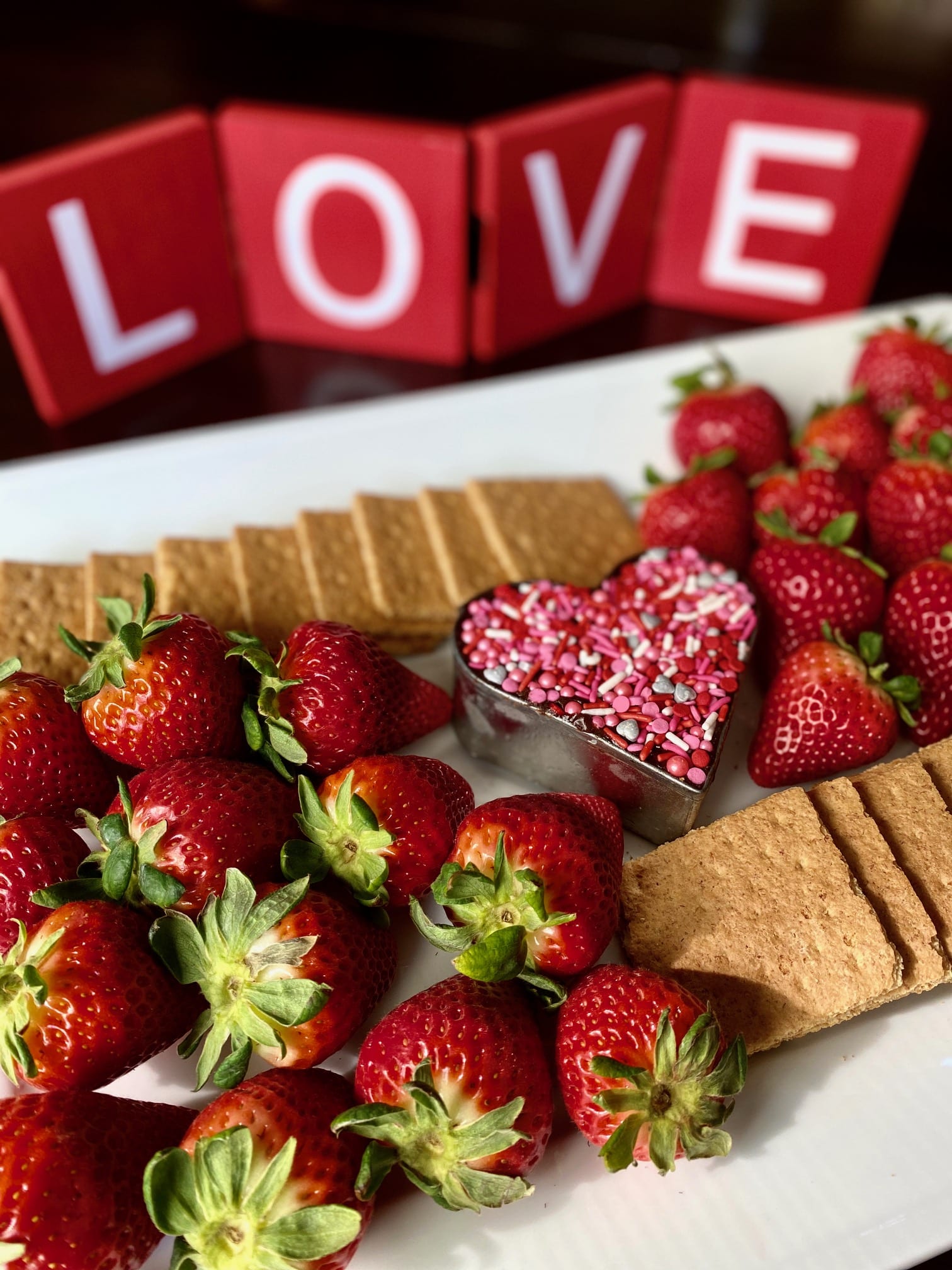Valentine's Day Healthy Snack Board of Strawberries Chocolate Hummus Graham Crackers and pink sprinkles for Sound Shore Westchester Moms Blog